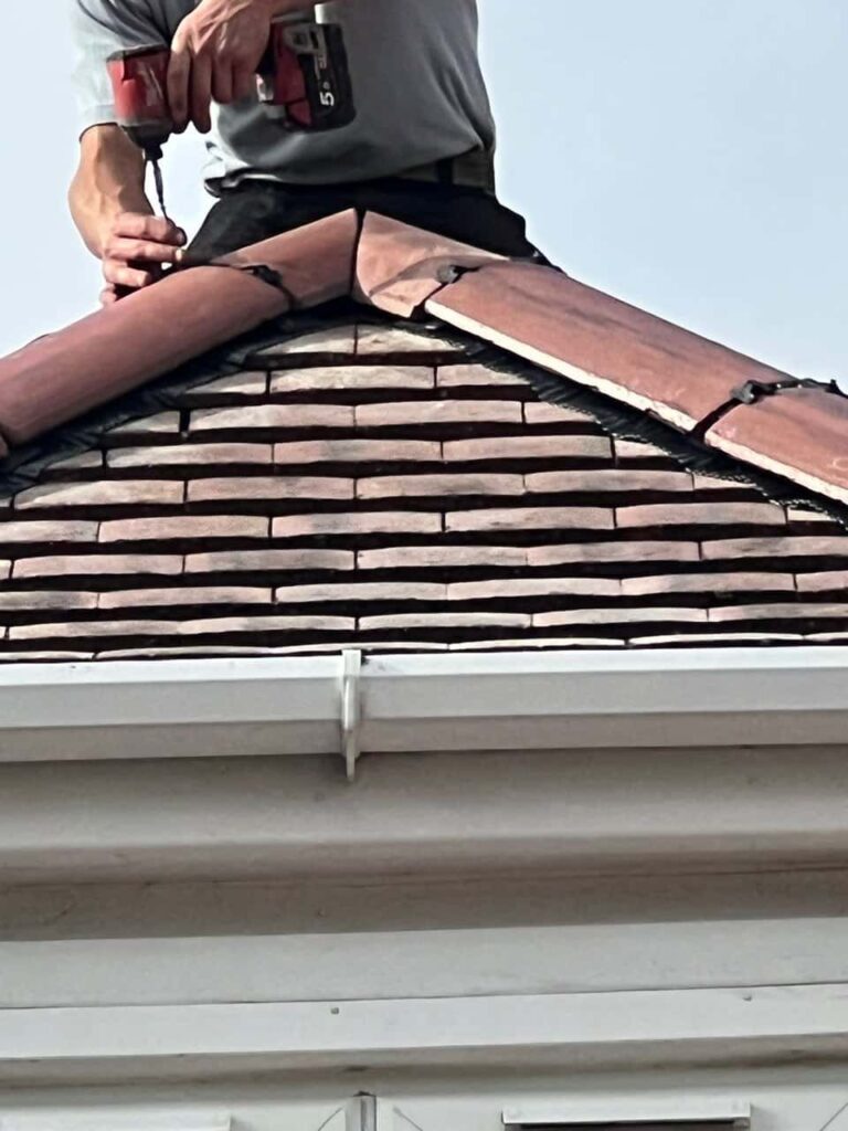 This is a photo of one of the operatives of Chislehurst Roofing Repairs installing new ridge tiles