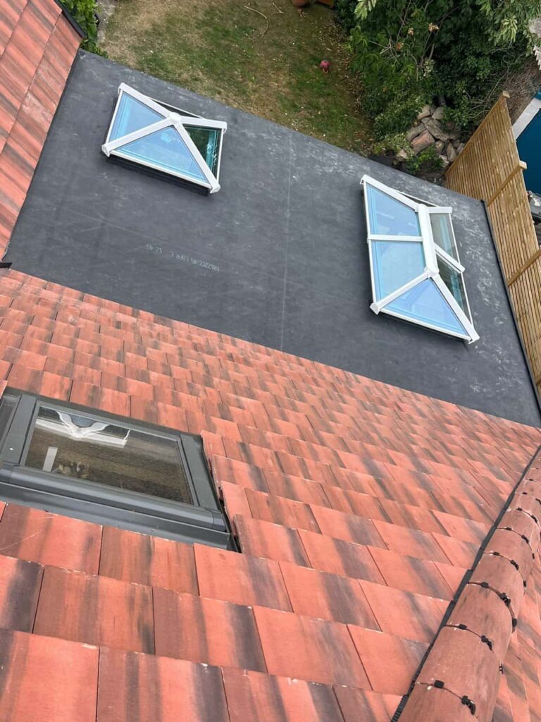 This is a photo taken from the roof ridge looking down a tiled pitched roof on to a flat roof. Works carried out by Chislehurst Roofing Repairs